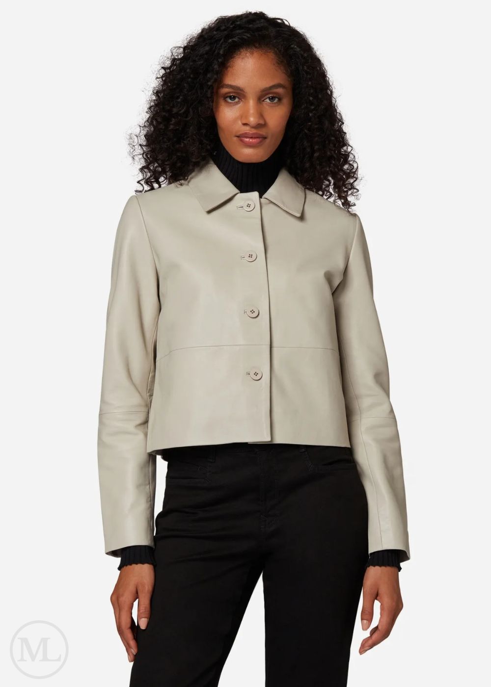 Woman wearing a lvory cropped jacket over a black outfit on a white background