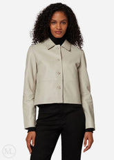 Woman wearing a lvory cropped jacket over a black outfit on a white background