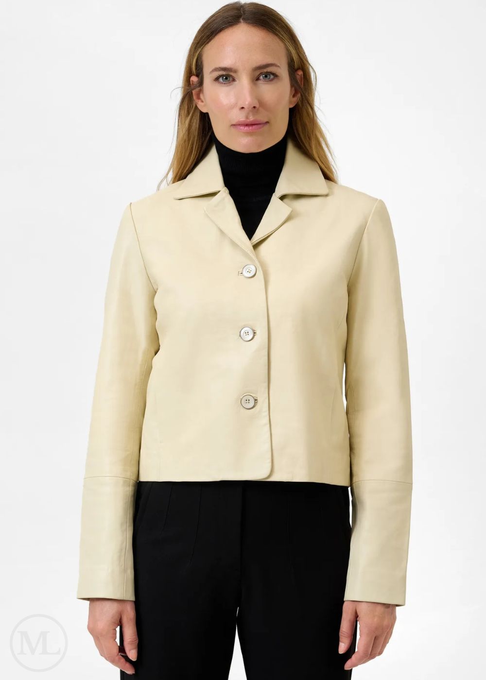 Woman wearing a lvory leather blazer jacket over a black turtleneck and pants on a white background