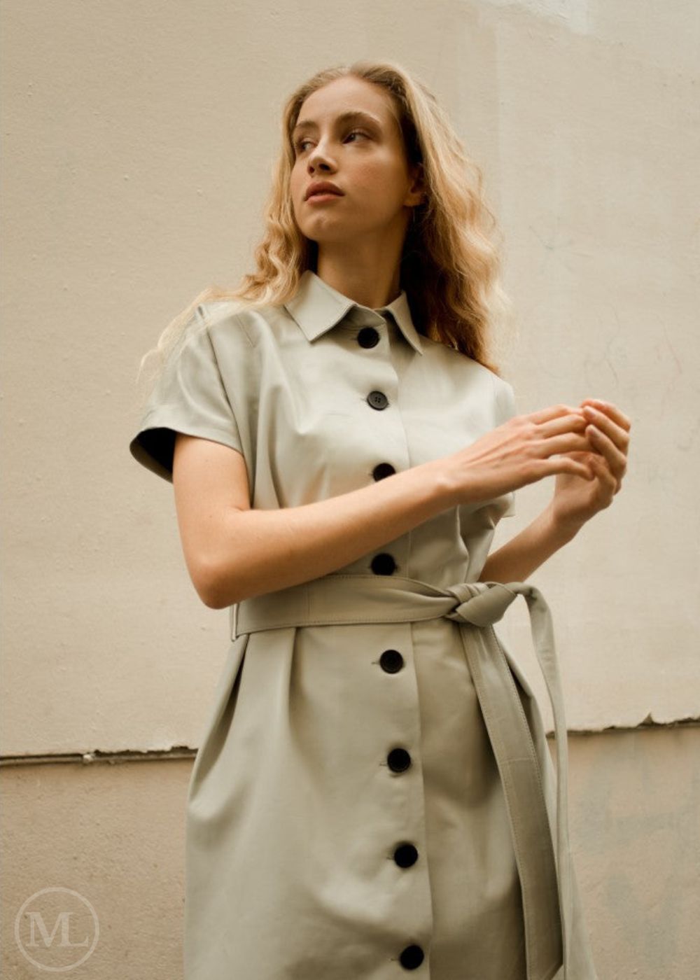 Woman wearing a beige real leather dress with black buttons against a plain background
